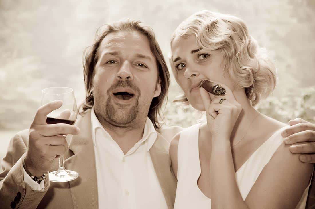 Hochzeitsfotograf fotografiert die Braut mit Zigarre und einem Hochzeitsgast